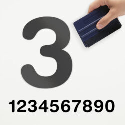 Een voorbeeld van onze losse plakcijfer in type rond. Het is het grijze cijfer drie, aangebracht door iemand die een rakel vast heeft.